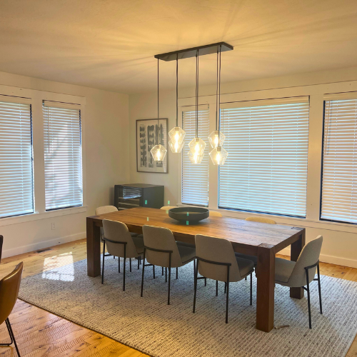 Window covering in dining room, with wooden table, chairs, and rug